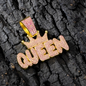 Goldener Queen Kronenanhänger mit rosa Strasssteinen auf schwarzem Holzhintergrund