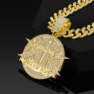 Macro detail of gold Cuban chain and King of Kings crown pendant with white zircons