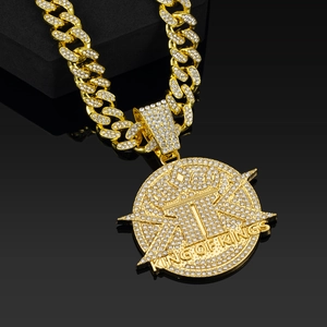Detail of gold Cuban link chain with King of Kings iced-out pendant on black background