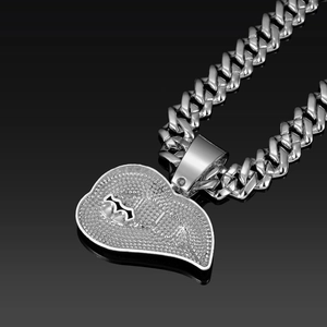 Detail van zilveren Cubaanse schakelketting met een hartvormige kristallen hanger