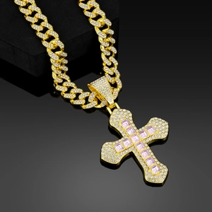 Macro shot of gold hip hop cross pendant with pink square stones on cuban link chain