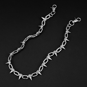 Nahaufnahme der Punk-Silber-Metallhose Kette mit scharfen Spikes auf schwarzem Lederhintergrund