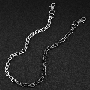 Macro shot of high-shine silver metal pant chain with lobster clasps on black leather background