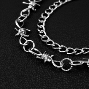 Détails de la chaîne à épines et maillons argentés sur cuir noir texturé