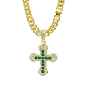 Detailed view of hip hop gold cross pendant with green square stones and cuban chain