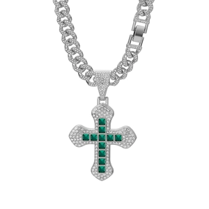 Macro view of silver hip hop cross pendant with green square gems and cubic zirconia