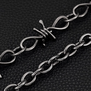 Detail of gunmetal barbed wire and O-link chain over black lychee leather background