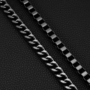 Close-up of industrial gunmetal Cuban link and box chain on black leather background