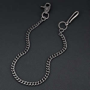 Detail of vintage silver pants chain with skull lobster clasp on black leather background