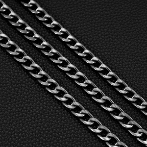 Macro shot of triple-layered dark gunmetal curb chains on a textured black leather background