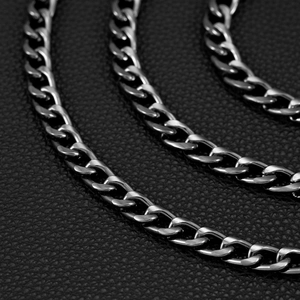 Macro detail of triple layered silver cuban chain links on black leather background