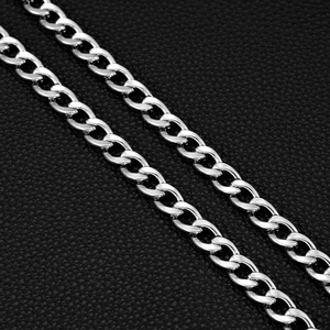 Macro shot of silver high-polished curb chain links on a black leather texture background
