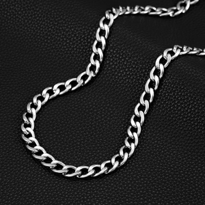 Macro shot of silver Cuban link chain with polished finish on black leather texture