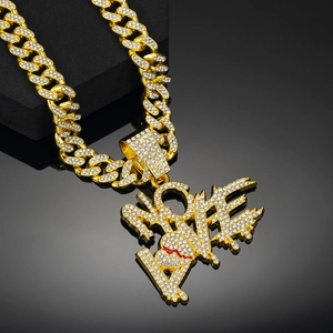 Gros plan d'une chaîne cubaine en or hip hop avec pendentif LOVE et cœur rouge serti