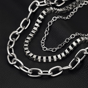 Close-up of triple-layered silver hip-hop chain with bold links on black leather texture