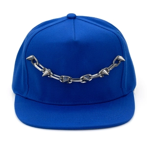 Détail de la casquette snapback bleu roi avec chaîne en métal argenté et clous punk