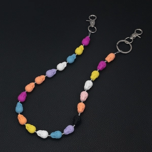 Colorful matte skull bead chain with metal lobster clasps on black leather background