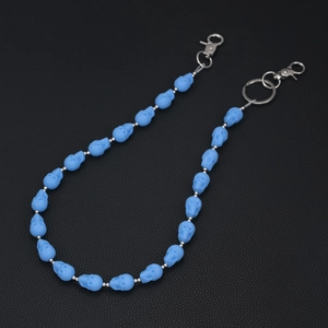 Macro shot of matte blue resin skull beads and silver clasp on a punk style denim chain