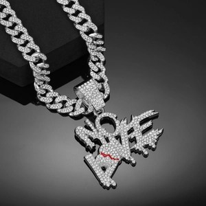 Gros plan du pendentif LOVE avec cœur rouge brisé sur chaîne Cuban link argentée