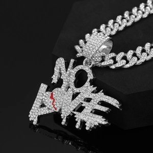 Vue macro d'une chaîne cubaine argentée avec pendentif NO LOVE et détail de cœur rouge brisé