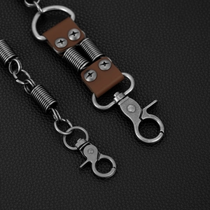 Detail of vintage silver biker chain with spring hooks and brown leather on black texture