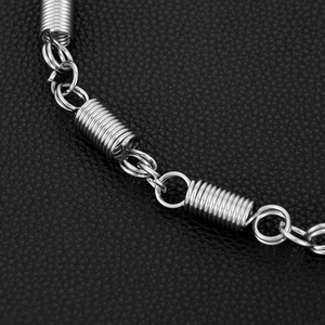 Close-up of silver metal chain with industrial spring joints on black leather background