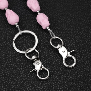 Pink matte skull bead keychain with silver lobster clasp on black leather background