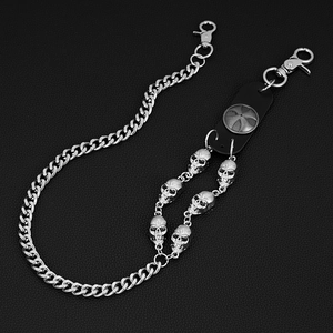 Detail of silver punk pant chain featuring skull pendants and cross leather strap