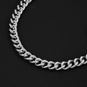 Macro shot of polished silver Cuban chain link texture on black leather background