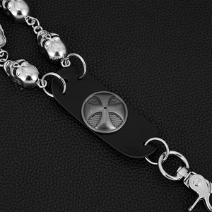 Detail of punk trousers chain featuring silver skull links and iron cross leather patch