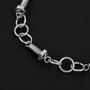 Macro detail of industrial style silver screw link chain on black leather background