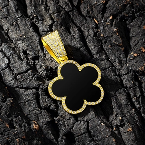 Close-up of golden five-petal flower pendant with black shell inlay and pavé crystals