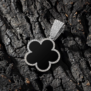 Macro shot of black enamel clover pendant with micro-paved white zircons on dark background