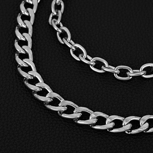 Close-up of polished silver hip hop chains on black leather, showing fine link details
