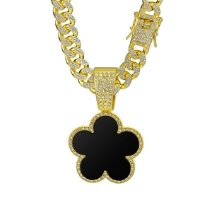 Close-up of golden Cuban link chain with a diamond-paved black clover pendant jewelry