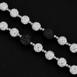 Macro shot of 14mm Shamballa crystal disco balls and silver beads on a black leather surface