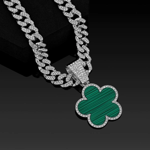 Detail of silver Cuban link necklace with iced out chain and green flower pendant