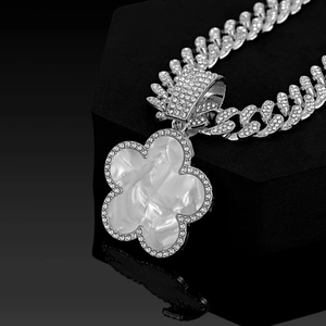 Macro side view of silver Cuban chain with five-leaf clover pendant and white faux shell inlay