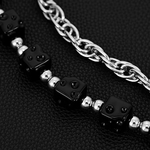 Detailed macro view of black dice beads and silver metal chain on dark leather