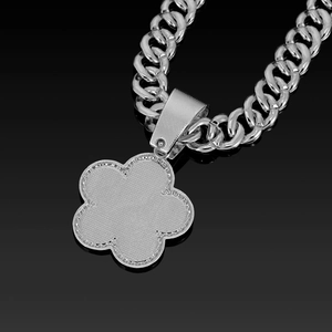 Macro detail of silver Cuban link necklace featuring a textured five-leaf flower pendant