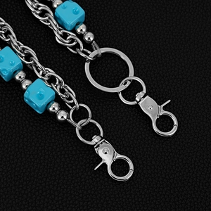 Detail of blue dice charms and silver metallic chain on a textured black leather background