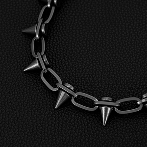 Gros plan d'une chaîne punk en métal à pointes avec finition noir mat sur cuir noir