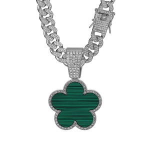 Detailed macro view of the silver Cuban link chain with a green clover pendant and crystals
