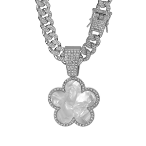 Macro detail of silver Cuban link necklace with iced-out clover pendant and shell inlay
