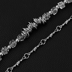 Detail of silver spiked trouser chain with clear crystal beads on black leather backdrop