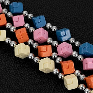 Detail of colorful geometric interlocking cubes and silver metallic beads on black leather