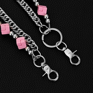 Detail of silver double-layered hip hop pant chain with pink dice on black leather background