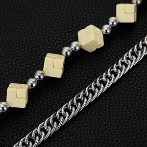 Detail of silver cuban chain and dice beaded accessory on black leather texture