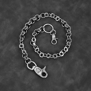 Detail of silver skull clasp and hexagonal nut link chain on black leather background
