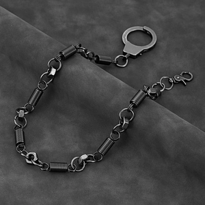 Industrial punk pant chain with handcuff clasp and metal nuts on grey leather background